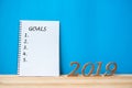2019 Happy New years with notebook Ã¢â¬Å Goals Ã¢â¬Å text and wooden number on table and copy space. Royalty Free Stock Photo